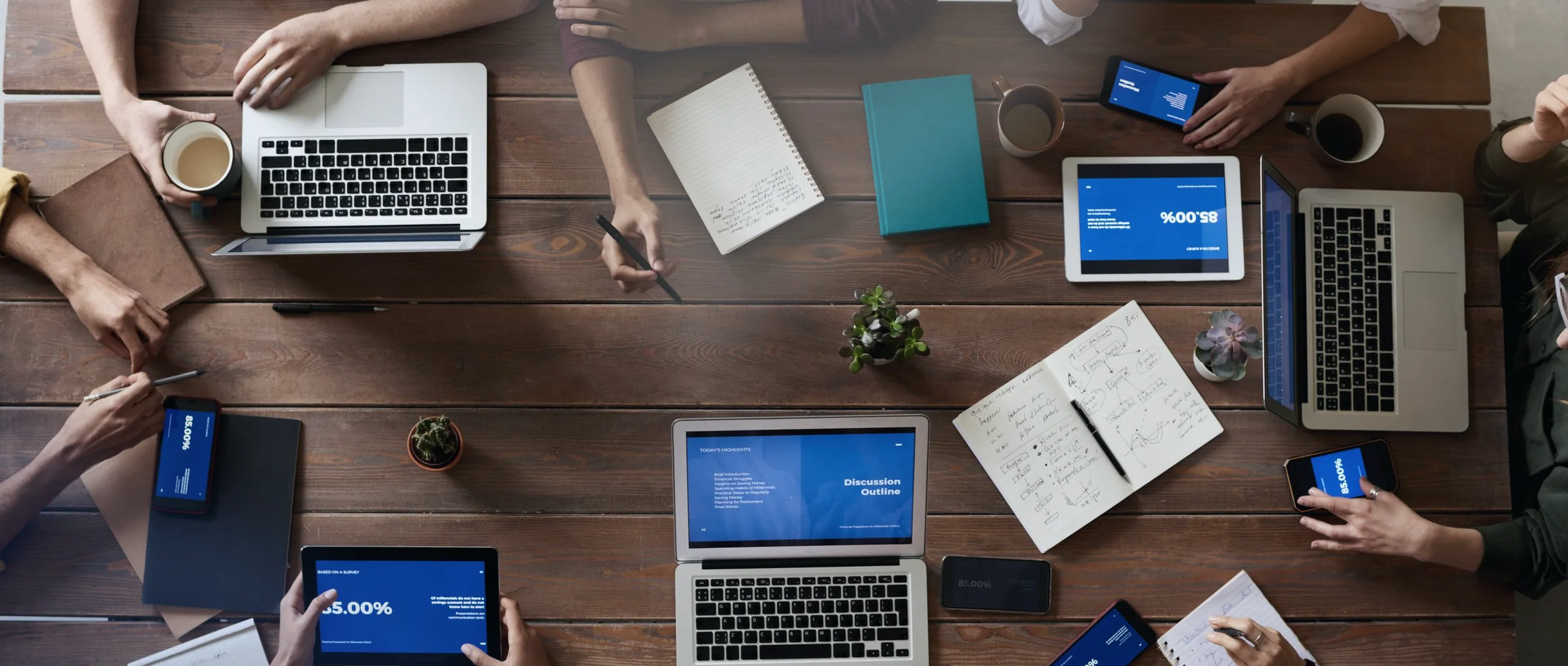 A team at work around one table: laptops, notes, the day's questions moving