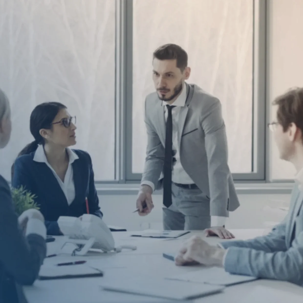 A review meeting in a modern office, one reviewer walking the table through the controls.