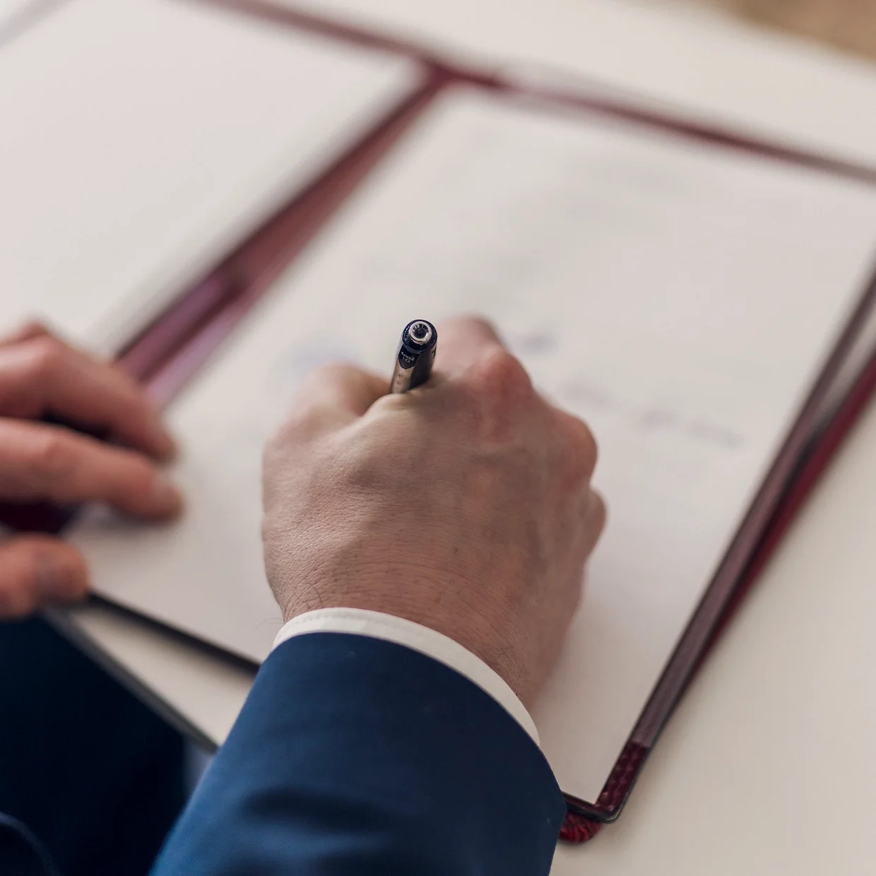 A hand signing inside a bound document folder.
