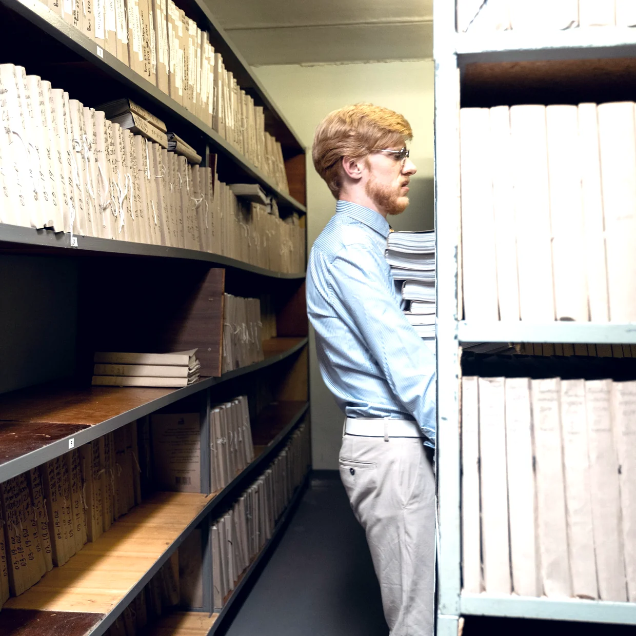 An archivist shelving bound registers.