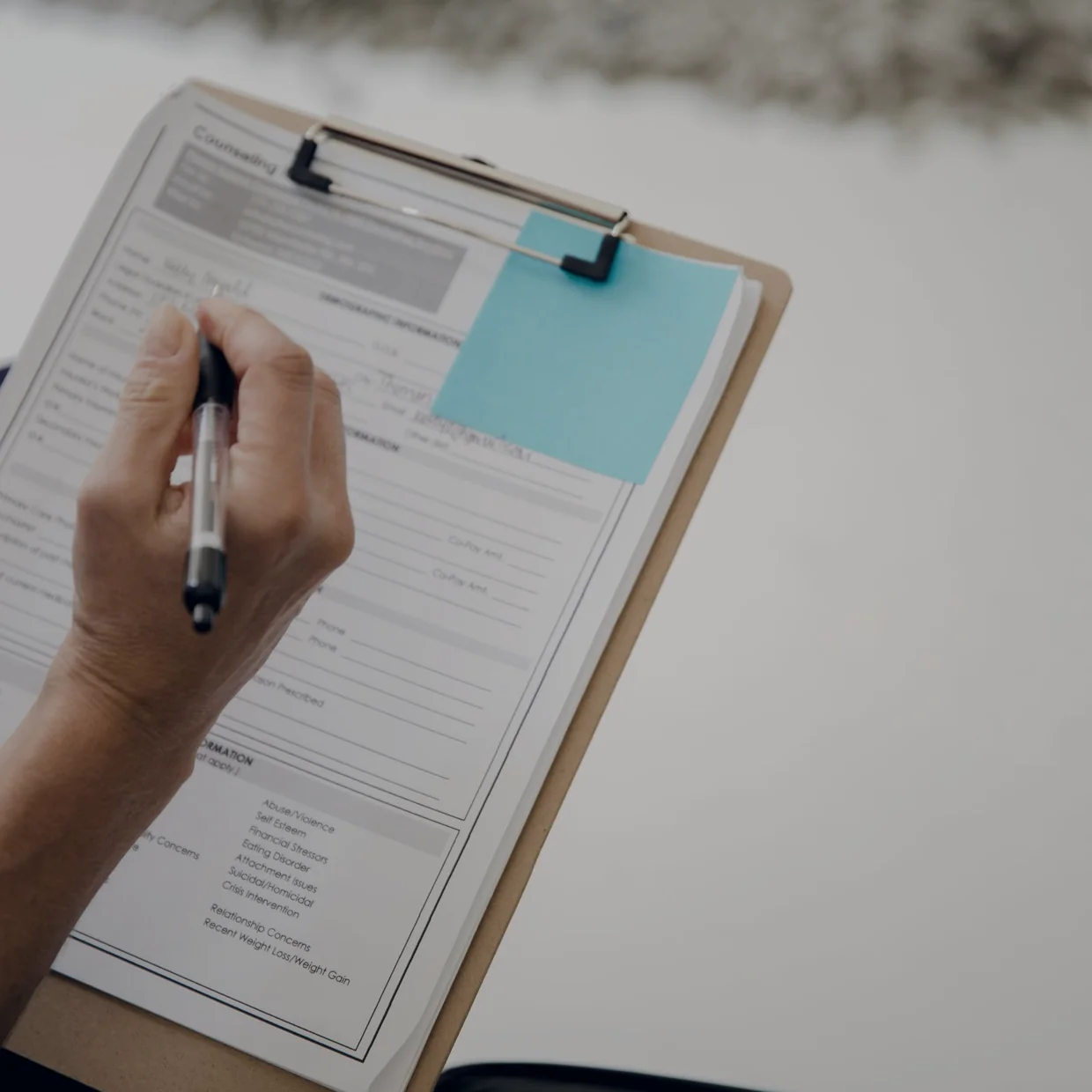 A hand working through a form on a clipboard.
