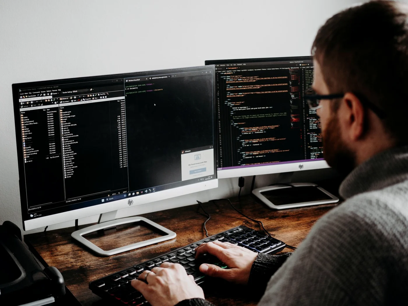An engineer at a desk, focused on code across two monitors.